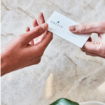 two hands exchanging a sollis health business card over marble background
