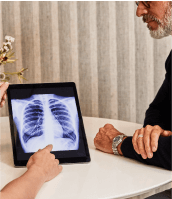 sollis employee sitting with patient, using tablet to show an xray of patient's lungs