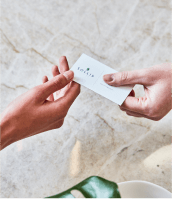 two hands exchanging a sollis health business card over a marble background